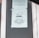 A printed notice taped to a window, indicating a preference for debit or credit card payments over cash. The sign includes a graphic of a hand holding a card. Another message is posted above, possibly policy or informational text.