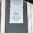 A printed notice taped to a window, indicating a preference for debit or credit card payments over cash. The sign includes a graphic of a hand holding a card. Another message is posted above, possibly policy or informational text.